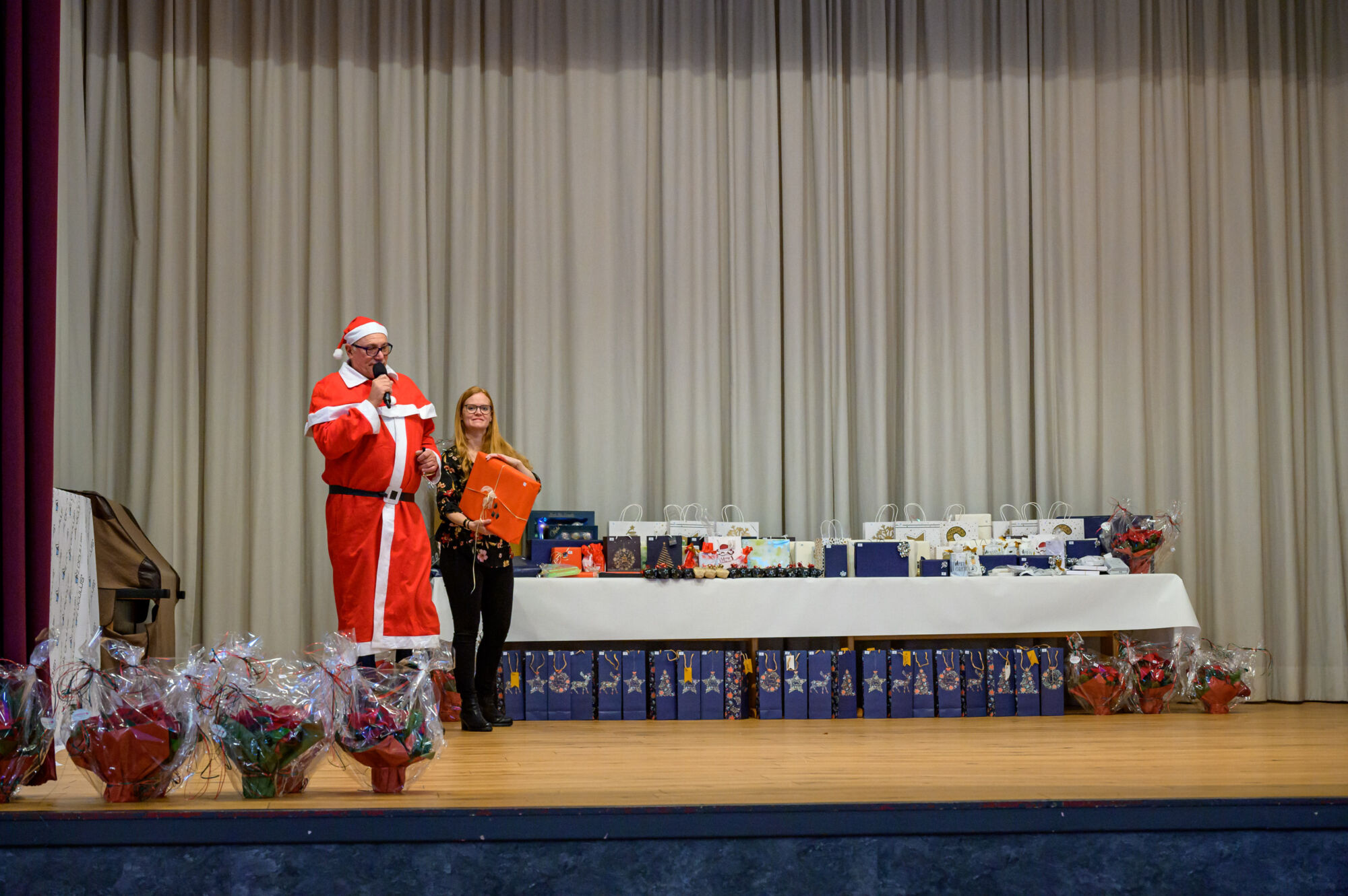 Der Weihnachtsmann und die Assistenz der Geschäftsleitung verteilen die Tombolagewinne