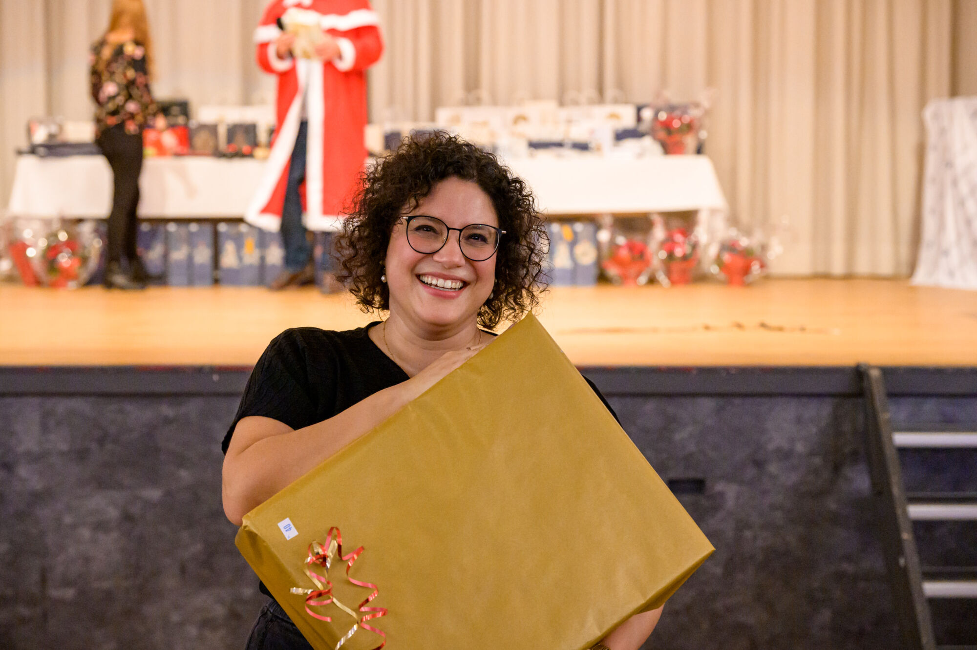 Lachende Frau mit Weihnachtsgeschenk im Arm